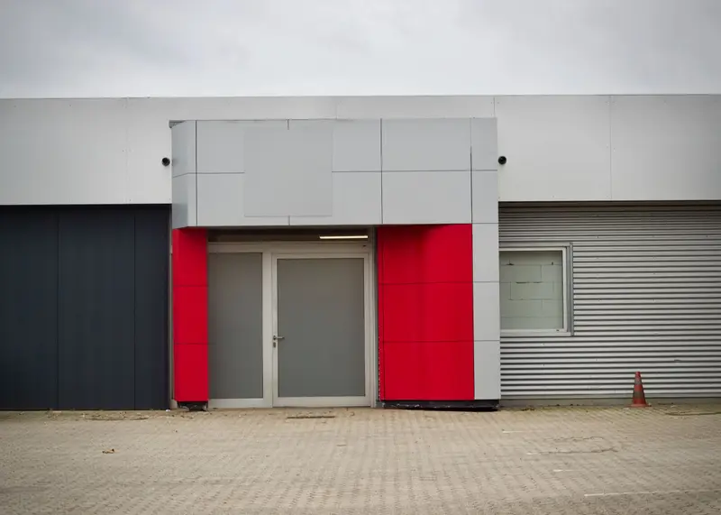 Ulaz poslovnog objekta s fasadom od aluminijskih panela i crvenim detaljima